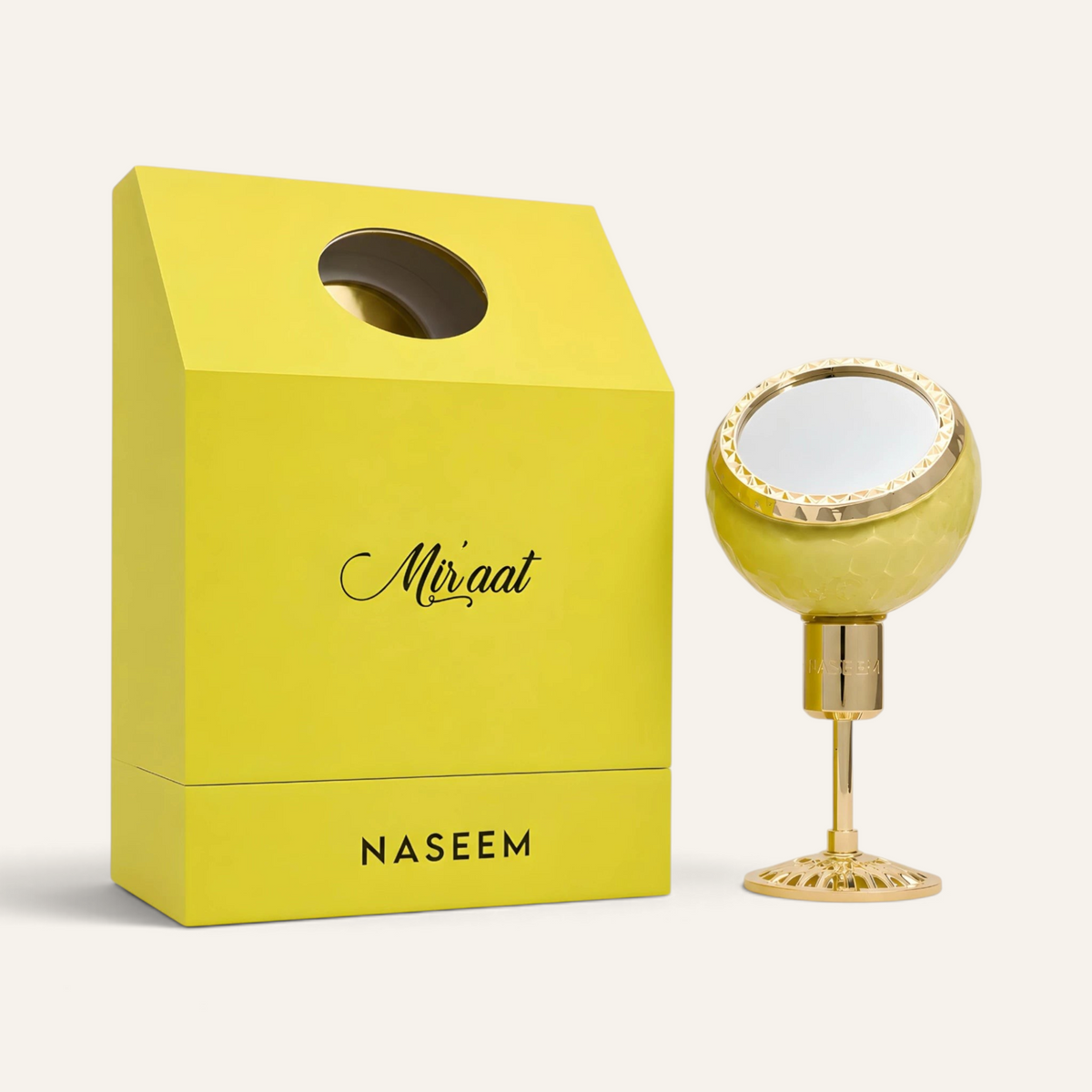Profumo maschile Miraat di NOOR Arabian Essence in flacone sferico dorato con specchio accanto alla scatola gialla